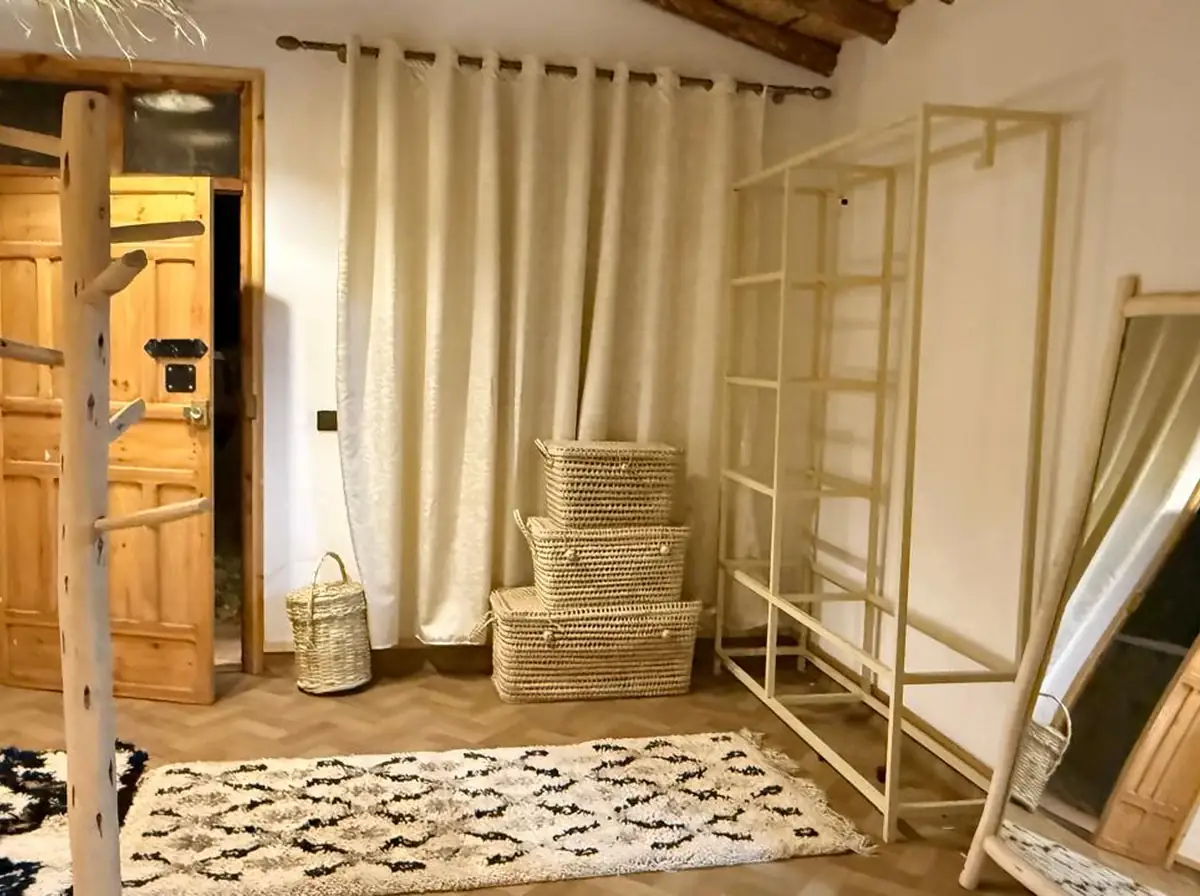 Un détail de la chambre avec le lit et le mur en plâtre chaud.